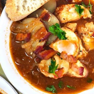 Fish stew with a slice of bread at top corner. Shows fish, egg, bacon