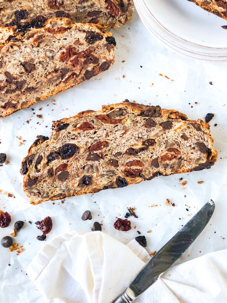 Slice of chocolate cherry pecan bread, with knife, napkin and more slices in background