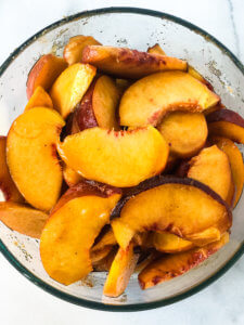 Process shot for Peach Crisp trifle showing peaches being prepared with brown and white sugars and lemon juice