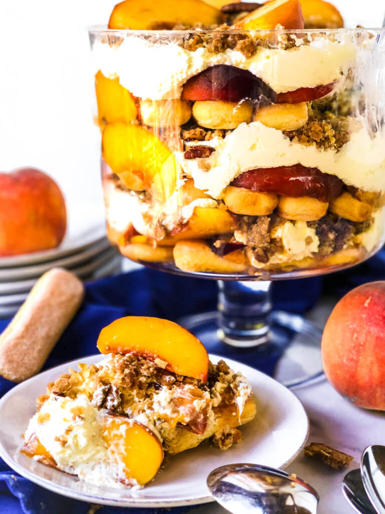 Shows slice of Easy Peach Crisp Trifle along with the 12-layered dish of trifle