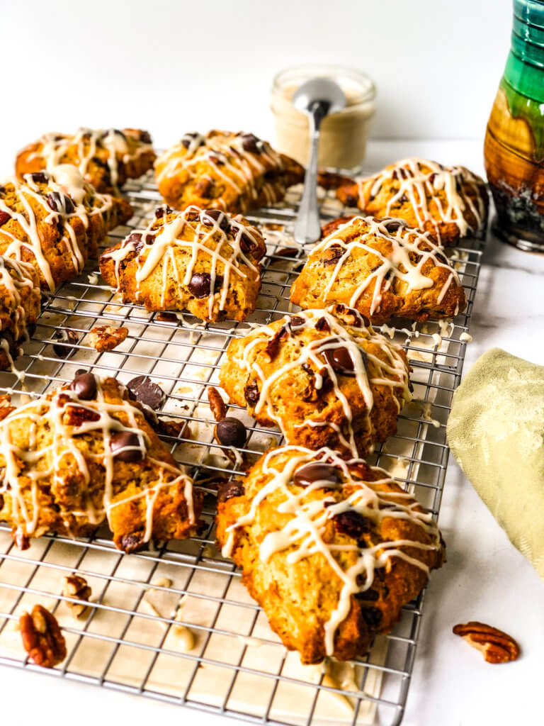 Tray of drizzled scones, showing 6 of them atop a tray, with a small jar of brown sugar glaze and a mug of coffee