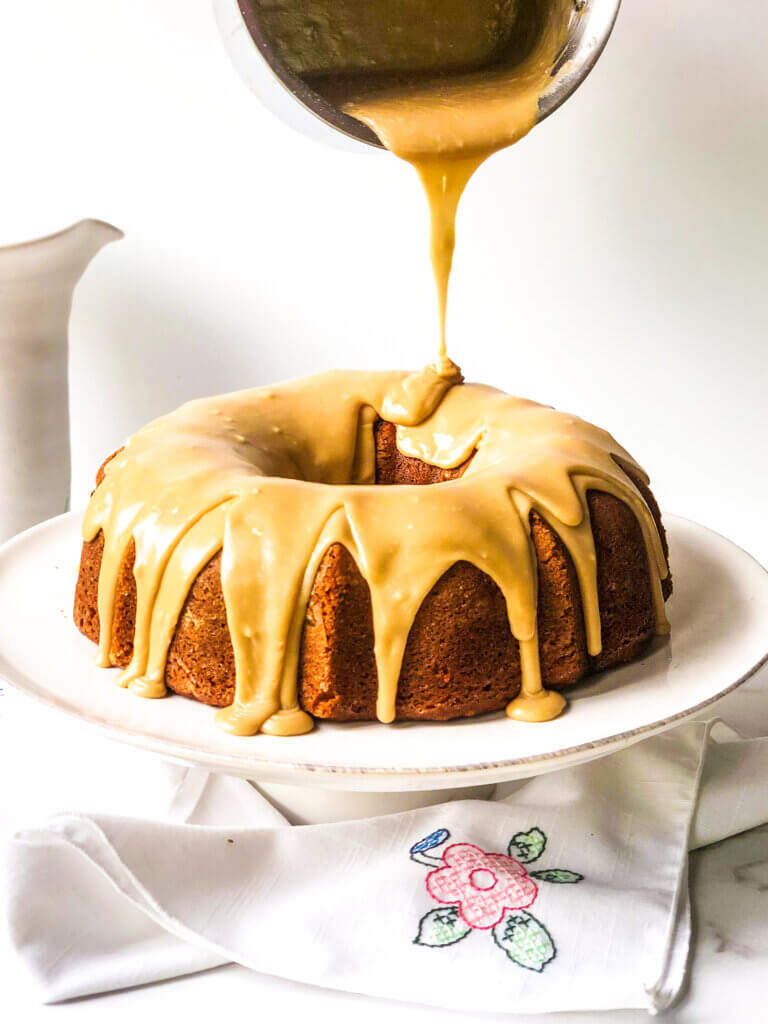 Blog photo showing caramel frosting being poured slowly over pumpkin bundt cake