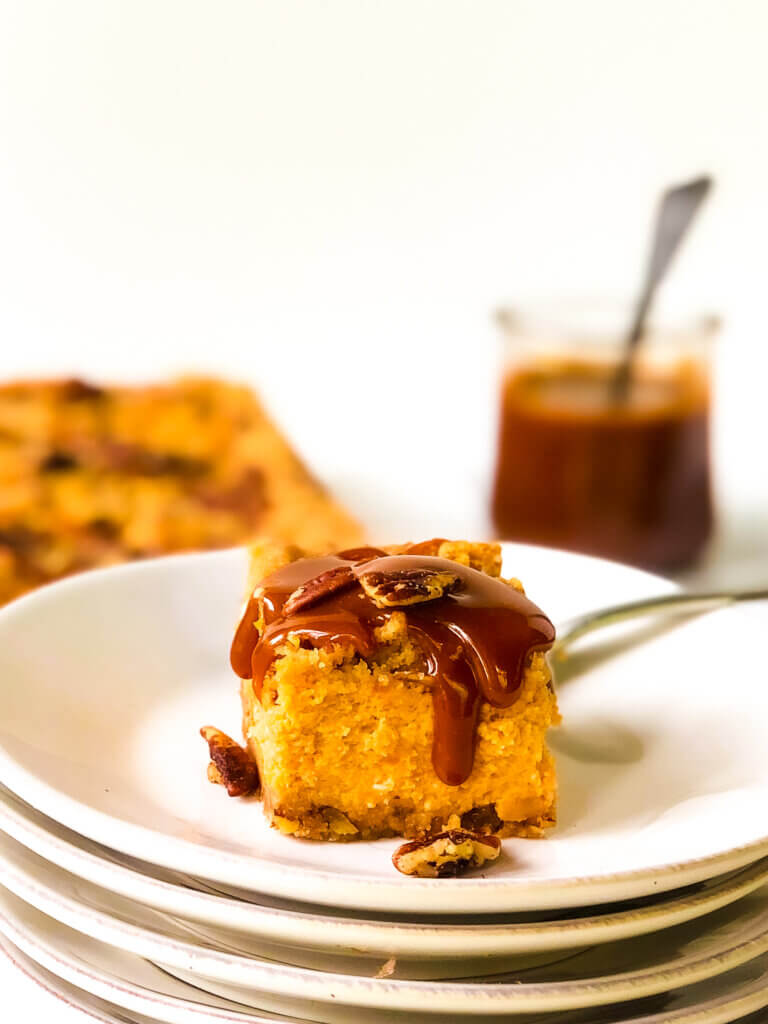 First photo in post shows bar of Sweet Potato Cheesecake covered with dripping caramel. Rest of bars and jar of caramel in background