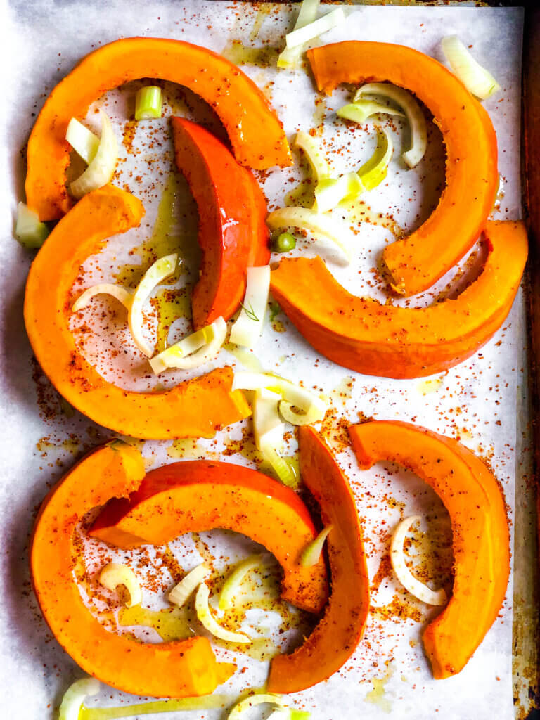 Shows Crescents of Squash and fennel slices, seasoned, on baking sheet