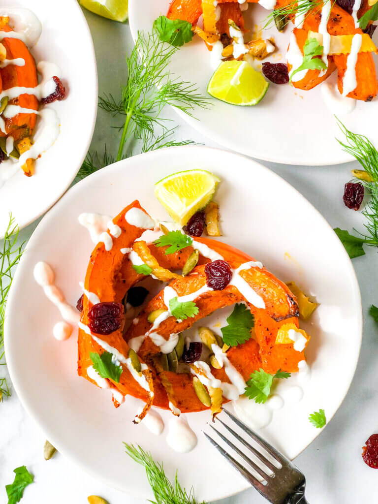 Overhead shot Shows dressed salads of red kuri squash crescents, dried cherries, and pepitas, all topped with creamy dressing