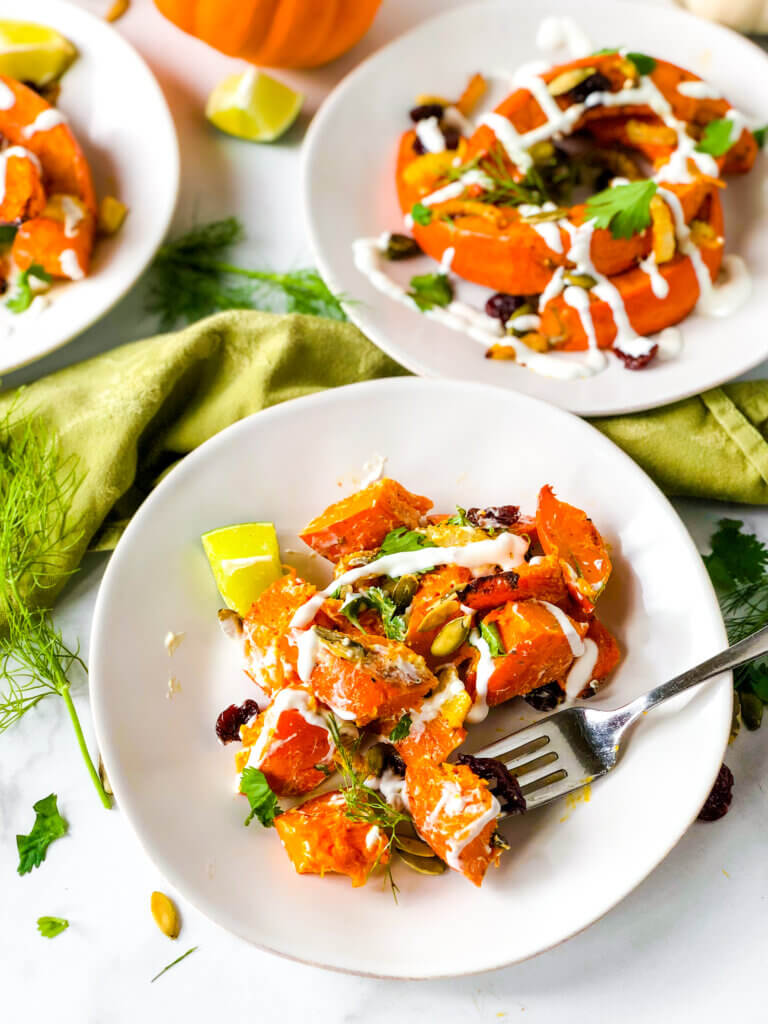 Shows dressed salads of red kuri squash crescents, dried cherries, and pepitas, all topped with creamy dressing