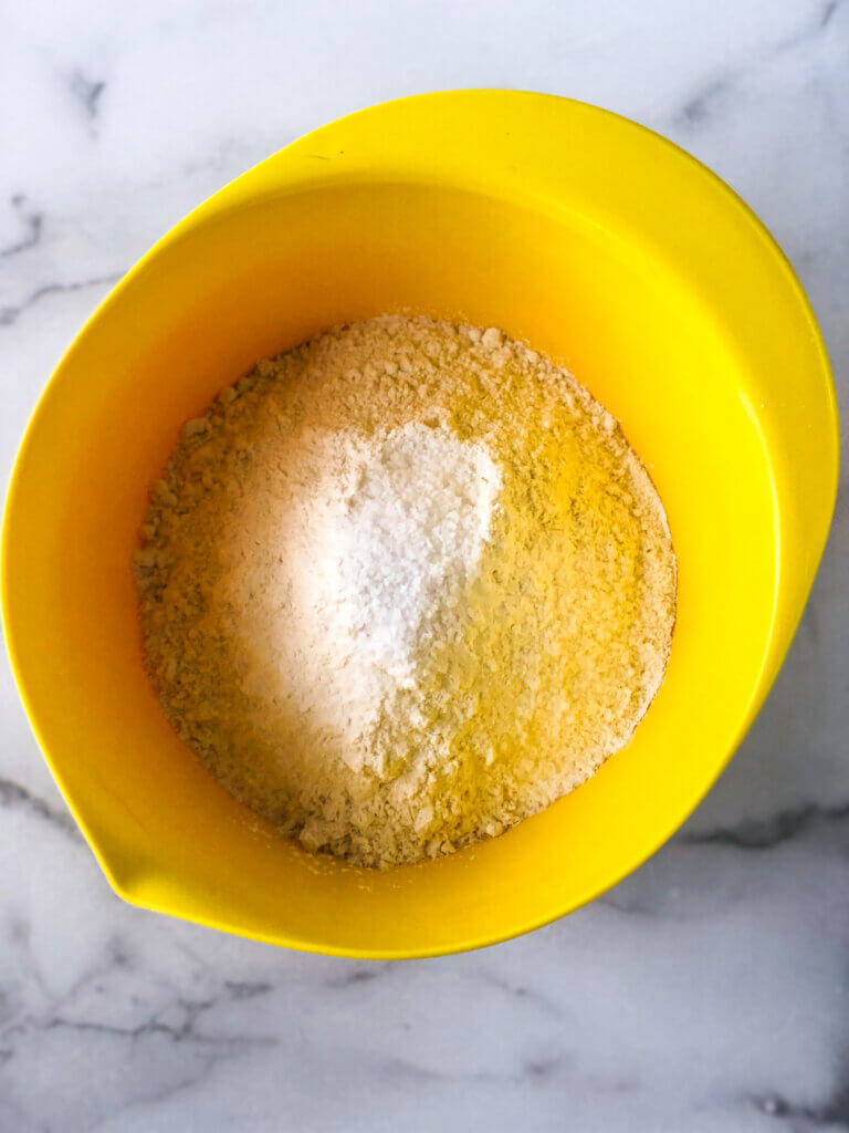 Process shot showing overhead view of flour and salt in a yellow bowl