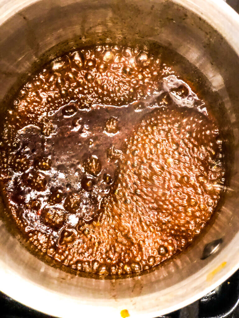 Process shot showing Overhead view of marinade reducing into a sauce in small saucepan