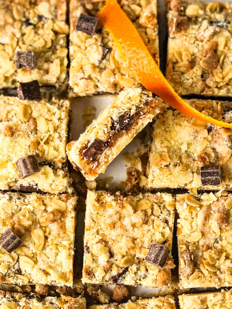 Overh3x3 grid of oat squares, with middle one turned on its side to show the layers of jam and chocolate