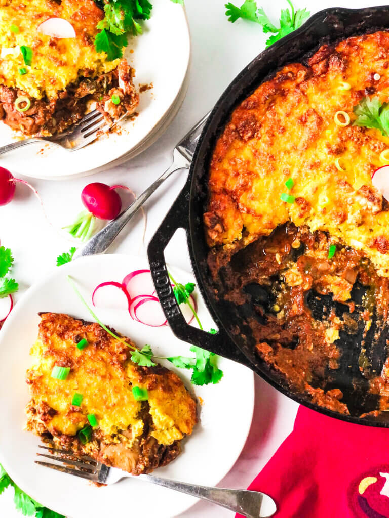 Crispy golden-yellow Chicken in Mole sauce, topped with crispy corn crust.  2 portions on plates.