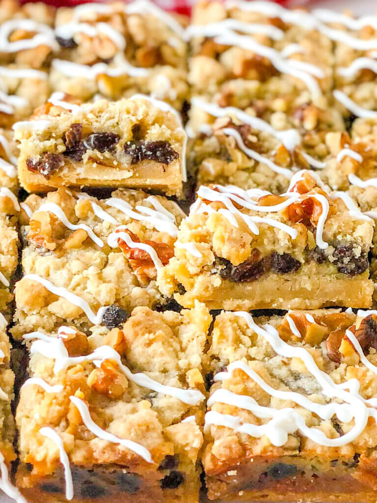 8 sliced sour cream raisin bar cookies with 2 propped up to display layers of crust, raisin-filled custard and crumbly topping with toasted walnuts