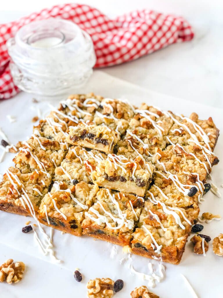 Sliced sour cream raisin bar cookies with 2 propped up to display layers of crust, raisin-filled custard and crumbly topping with toasted walnuts