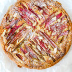 Rhubarb frangipane tart showing stripes of baked rhubarb, and toasted almonds and sprinkling of confectioners sugar