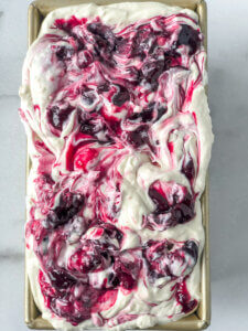 Pan is almost overflowing with ice cream swirled with cherry mixture